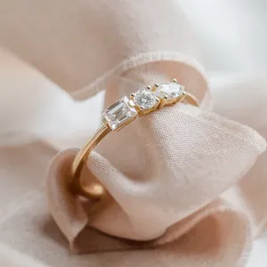 Close-up of AVELA gold ring with three lab-grown diamonds held in a gloved hand