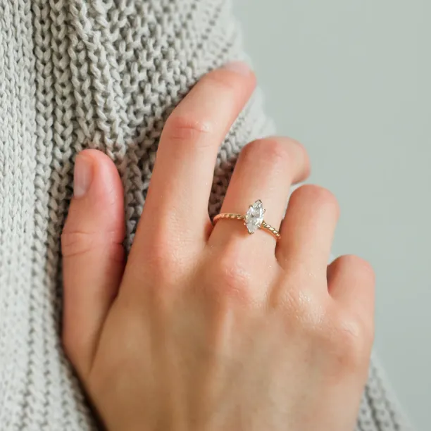 Gold twisted rope ring with marquise-cut moissanite worn on the hand