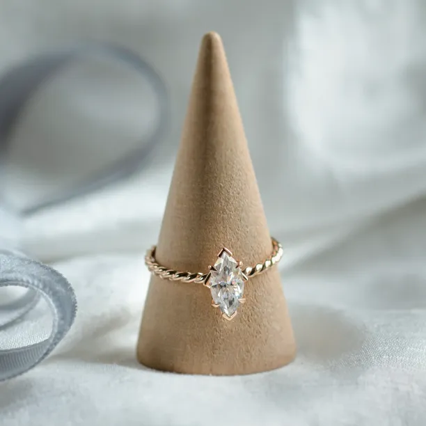 Gold twisted rope ring with marquise-cut moissanite on a display stand