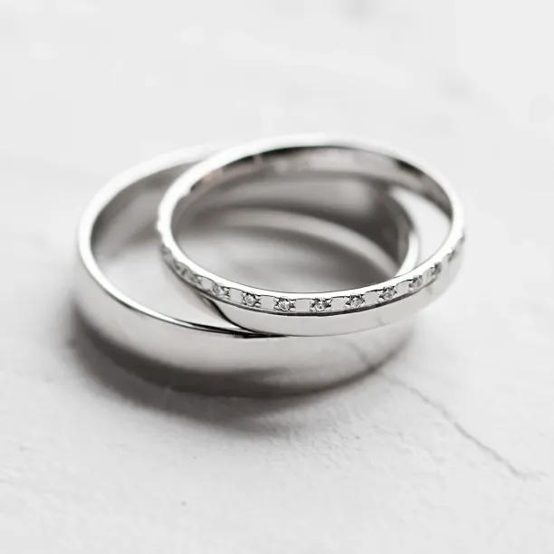 Close-up of TRADIZIONE wedding rings showing the diamond-set and plain bands