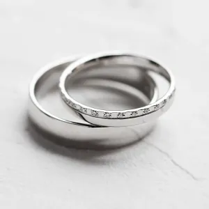 Close-up of TRADIZIONE wedding rings showing the diamond-set and plain bands