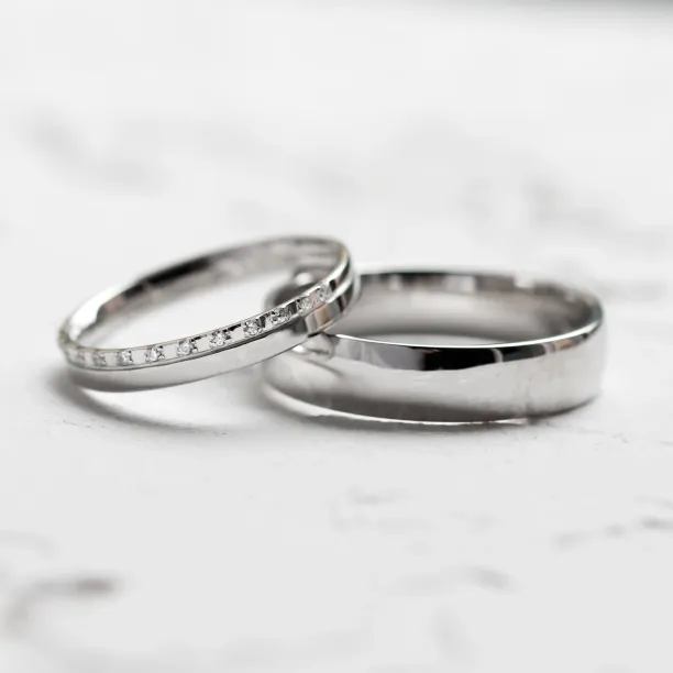 Angled view of TRADIZIONE wedding rings with a diamond-set and plain band