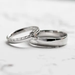 Angled view of TRADIZIONE wedding rings with a diamond-set and plain band