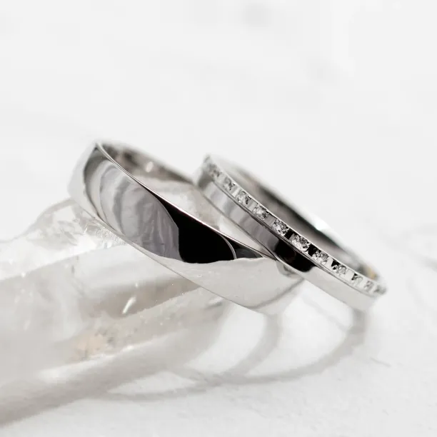 Close-up angled view of the diamond-set and plain TRADIZIONE wedding rings