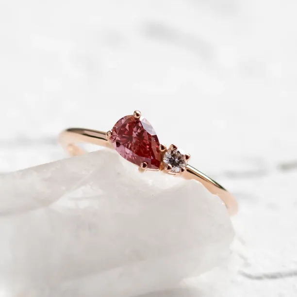 Detail růžového diamantu ve tvaru pear a kulatého bílého diamantu v prstenu DUA