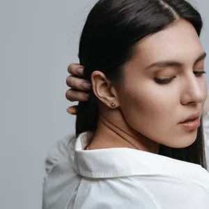 Gold hexagonal earring held against the ear
