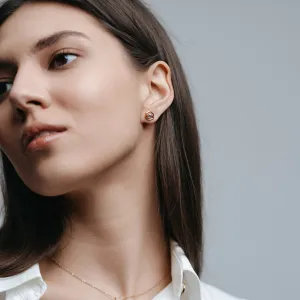 SAM gold hexagonal earring worn on the ear, shown in close-up