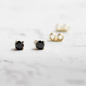 Close-up of black diamond stud earrings with butterfly backs behind them