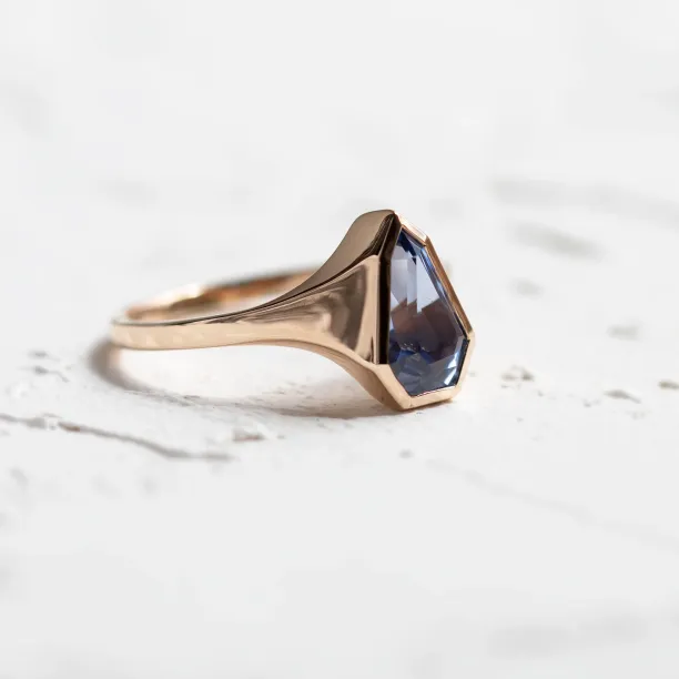 Angled view of the PLATON gold signet ring with blue sapphire