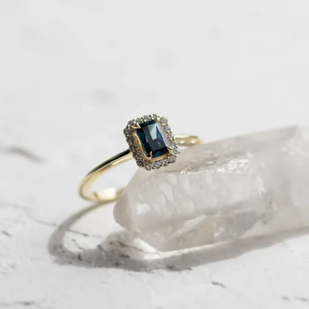 Angled close-up of the MILLIE ring with a blue radiant-cut diamond