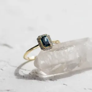 Angled close-up of the MILLIE ring with a blue radiant-cut diamond
