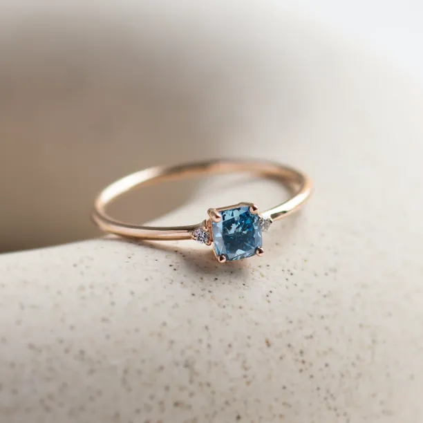 Angled view of the ARCTIS gold ring with a blue lab-grown diamond