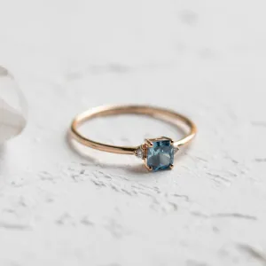 Angled close-up of the ARCTIS gold ring and cushion-cut blue lab-grown diamond