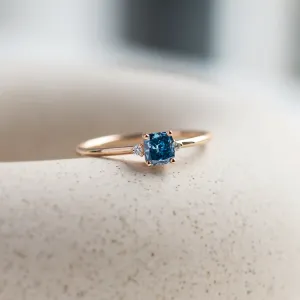 ARCTIS gold ring with a blue lab-grown cushion-cut diamond and white diamonds, close-up angled view