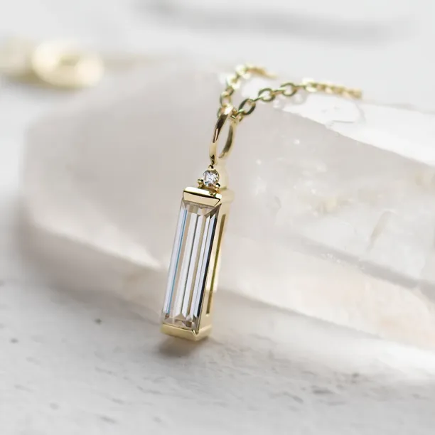 Close-up of the FELIANA gold pendant and its baguette moissanite