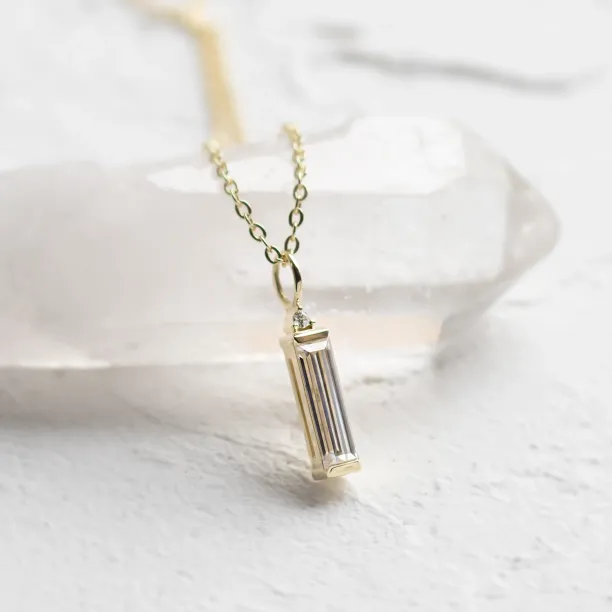 FELIANA gold pendant necklace in an angled view with baguette moissanite and diamond