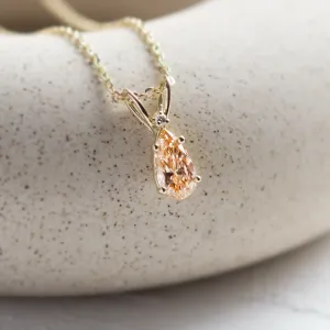 Close-up of the gold SOLARIS pendant's orange lab-grown pear-shaped diamond