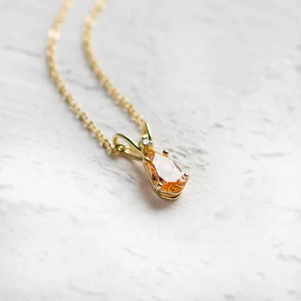Angled close-up of the gold SOLARIS pendant with orange lab-grown diamond