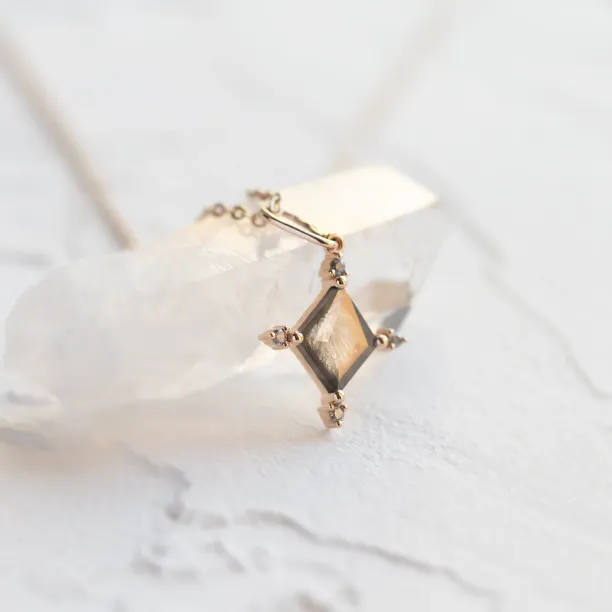 Angled close-up of the CRESSIDA necklace pendant and its faceted salt and pepper diamond
