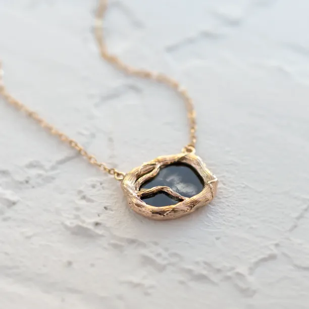 Angled close-up of the TREASURE gold necklace with salt and pepper diamond