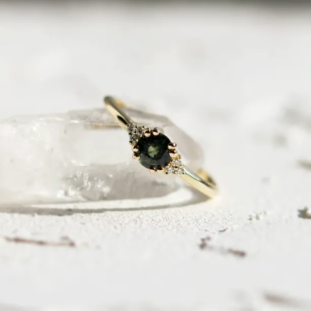 Detailní šikmý pohled na zásnubní prsten se zeleným safírem a diamanty