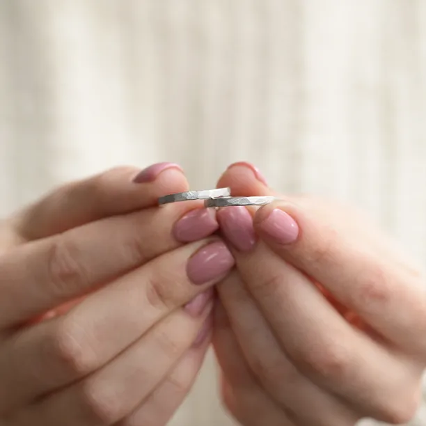 ETA hammered platinum wedding bands held between fingers