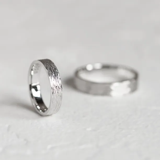 Platinum wedding bands with textured surfaces, one ring in sharp focus