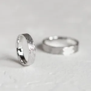 Platinum wedding bands with textured surfaces, one ring in sharp focus