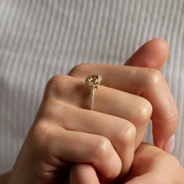 Zlatý prsten GISE s přírodním safírem a diamanty v halo stylu držený mezi prsty