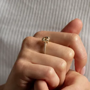 Zlatý prsten GISE s přírodním safírem a diamanty v halo stylu držený mezi prsty