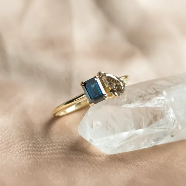 Angled view of the DOLORES ring with blue emerald and brown pear diamonds