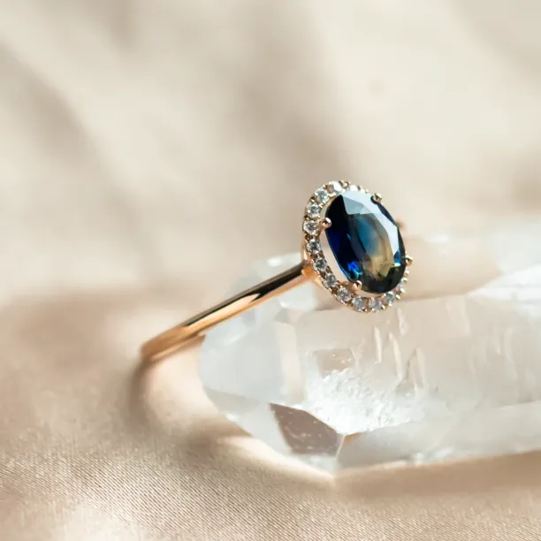 Close-up of the ZARIA halo ring with a faceted teal sapphire
