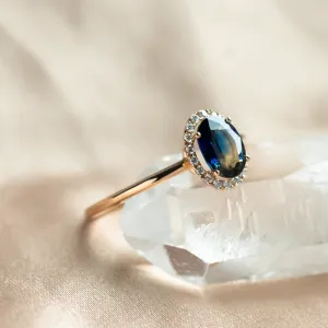 Close-up of the ZARIA halo ring with a faceted teal sapphire