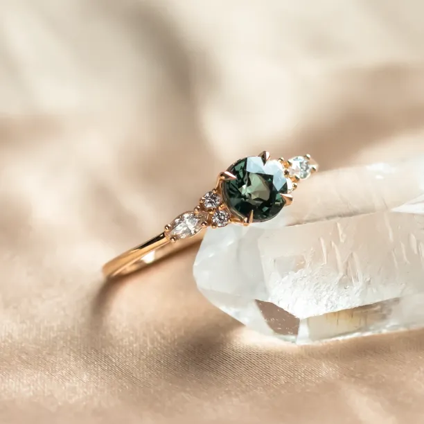 Angled close-up of the MAIDEN engagement ring with green sapphire and diamonds