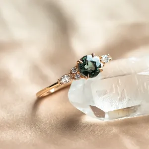Angled close-up of the MAIDEN engagement ring with green sapphire and diamonds