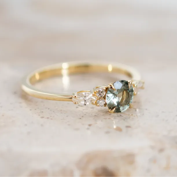 MAIDEN gold engagement ring with a natural green sapphire and diamonds, angled close-up