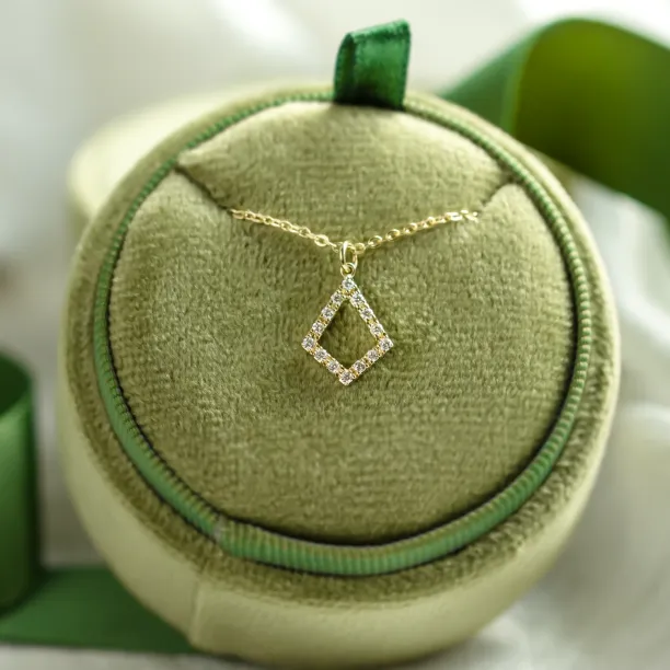 Gold necklace with lab-grown diamond kite pendant displayed on a cushion