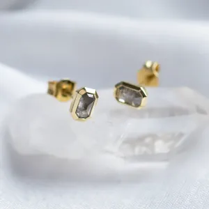 Angled view of NYLA gold stud earrings with salt and pepper diamonds