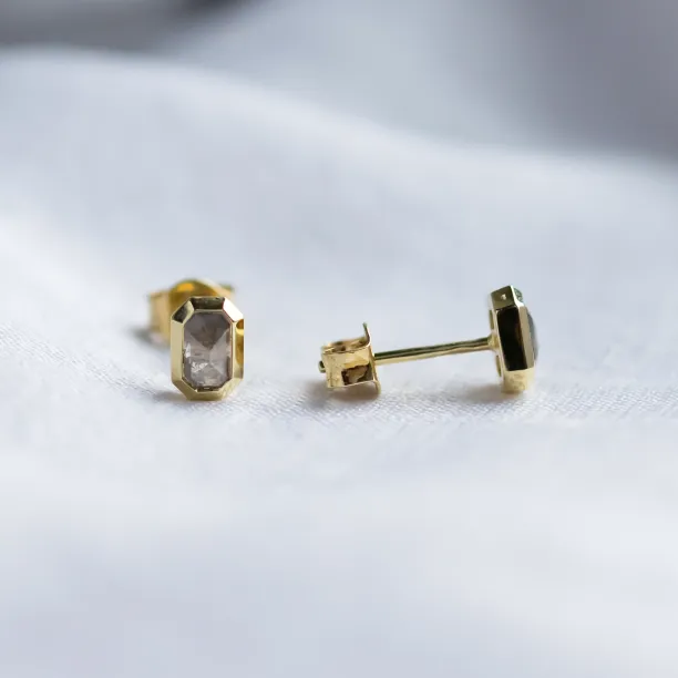 Close-up of NYLA gold stud earrings with hexagonal salt and pepper diamonds in bezel settings.
