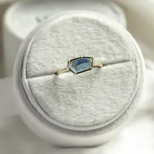 Angled view of the MAGNIFICA gold engagement ring with asymmetrical teal sapphire
