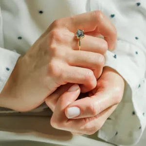MAGNIFICA gold engagement ring with teal sapphire and diamonds held between hands
