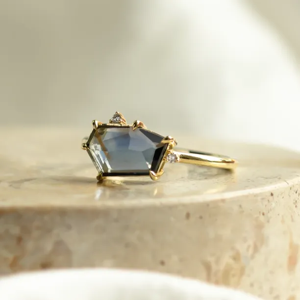 Angled view of the MAGNIFICA gold engagement ring with teal sapphire and diamond accents