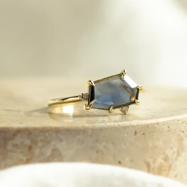 Close-up of the MAGNIFICA gold engagement ring with asymmetrical teal sapphire and diamonds