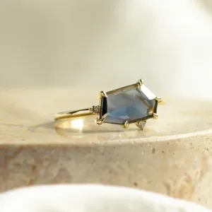 Close-up of the MAGNIFICA gold engagement ring with asymmetrical teal sapphire and diamonds