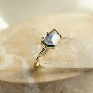 Angled close-up of the gold MAGNIFICA engagement ring with a teal sapphire and diamonds