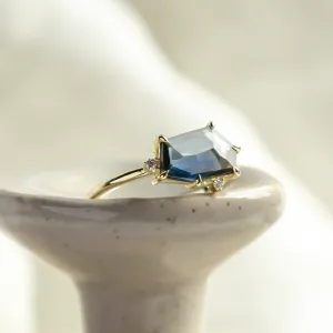 Close-up of the MAGNIFICA gold engagement ring with an asymmetrical teal sapphire and diamonds