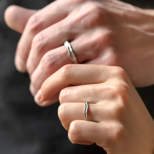 SAVANNAH matching wedding rings worn on two hands, showing their irregular surfaces