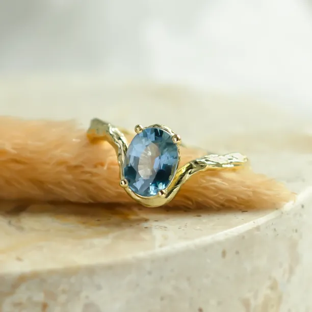 Close-up of KIARA gold ring with oval blue sapphire and branch-like band