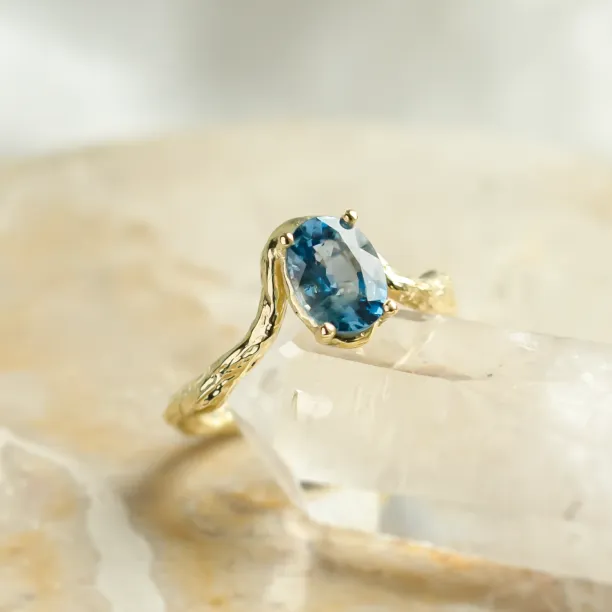 Angled close-up of KIARA ring showing oval blue sapphire and irregular band