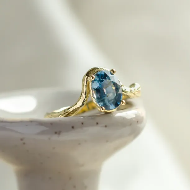 Close-up of the KIARA gold ring with an oval blue sapphire